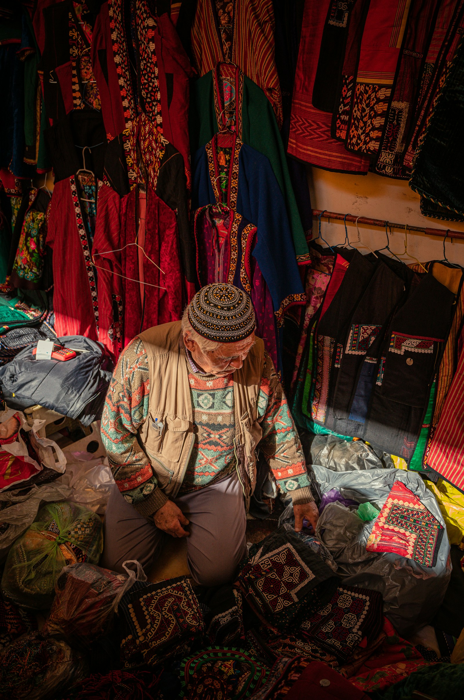A vendor seated before stacked goods at a local market.